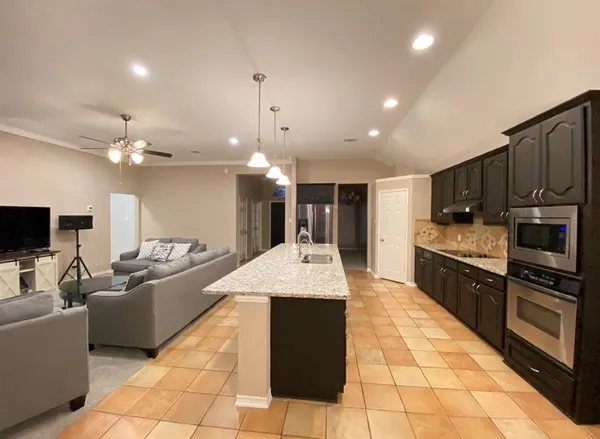 a large kitchen with kitchen island a large counter top stainless steel appliances and cabinets