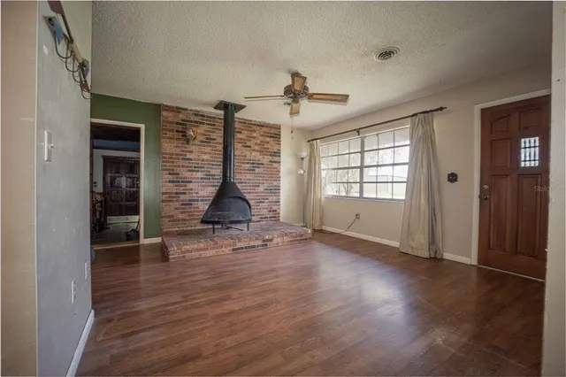 an empty room with wooden floor staircase and windows