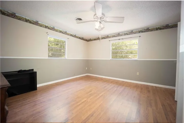 a view of an empty room with a window and wooden floor