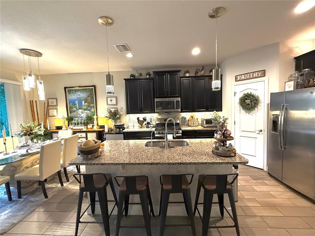 11104 Spring Point Circle Riverview, FL 33579 - Photo 17 of 52 a kitchen with kitchen island granite countertop a dining table chairs refrigerator and cabinets