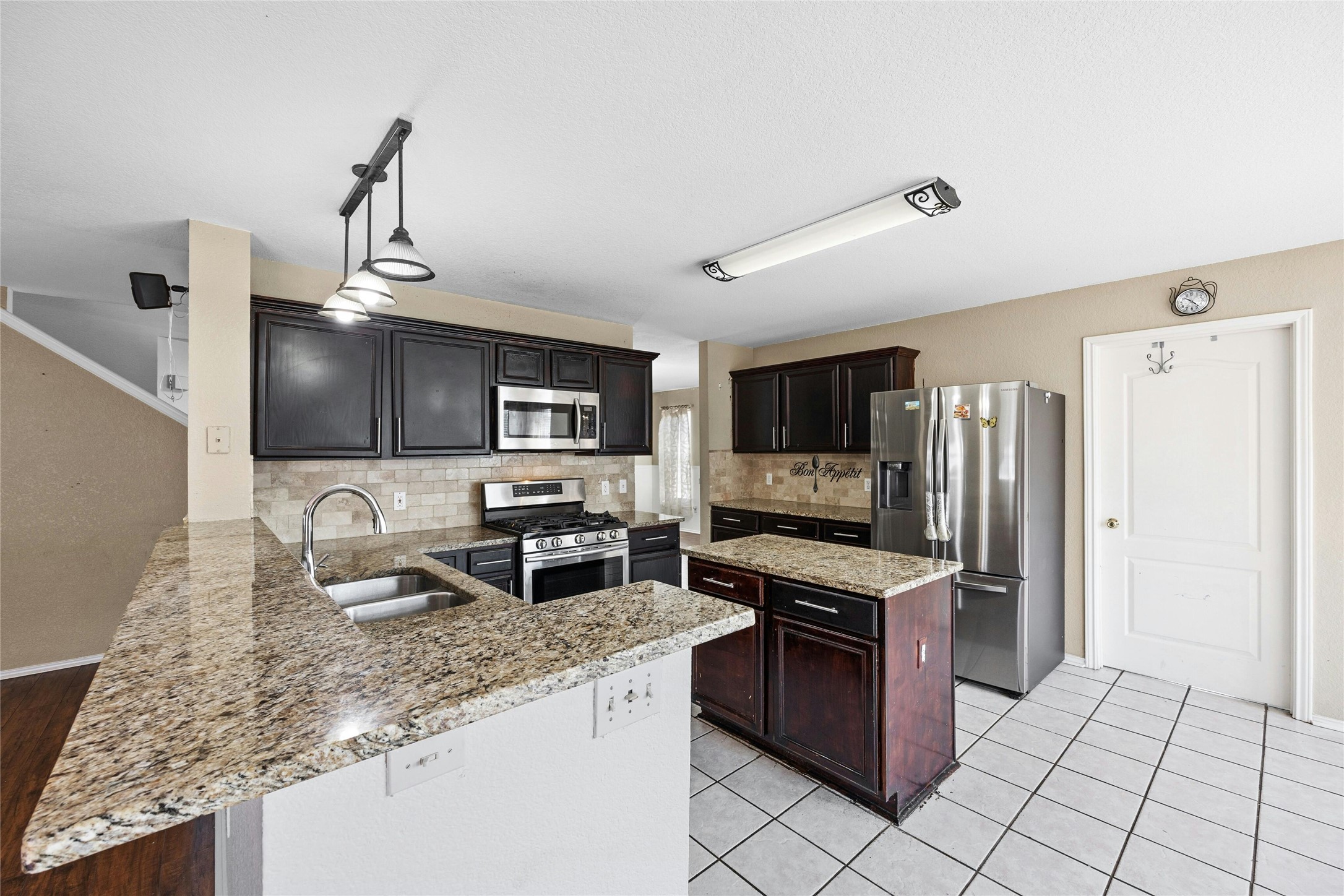 3618 Windhill Loop Round Rock, TX 78681 - Photo 8 of 30 Kitchen with stainless steel appliances, tasteful backsplash, a peninsula, hanging light fixtures, and light stone counters
