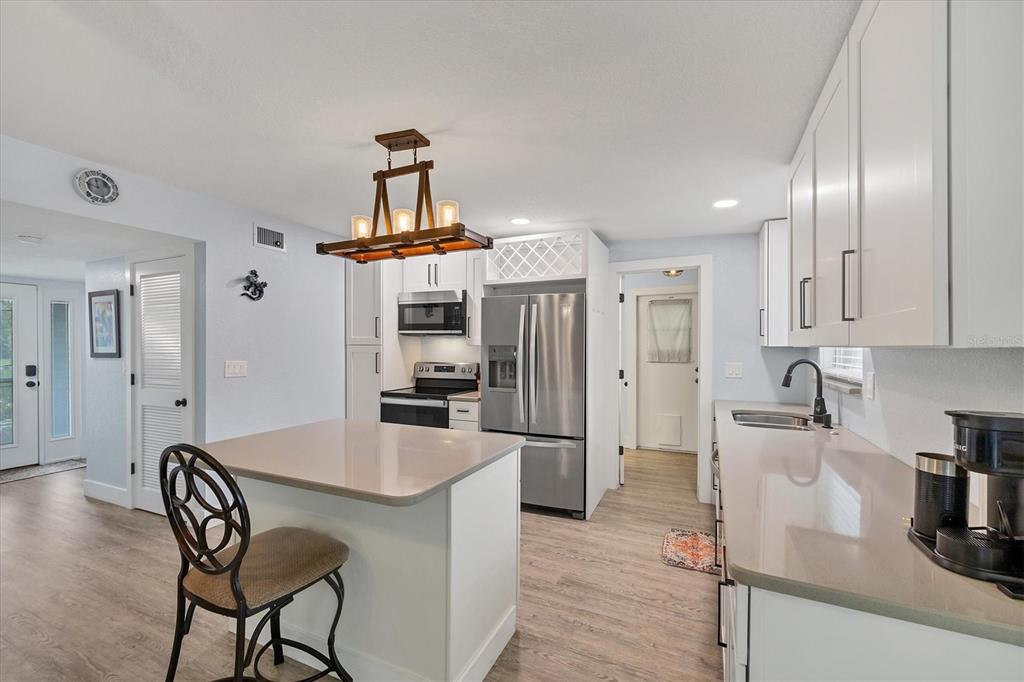 2254 Hayworth Road Port Charlotte, FL 33952 - Photo 5 of 48 a kitchen with stainless steel appliances kitchen island granite countertop a refrigerator a stove a sink dishwasher and white cabinets with wooden floor