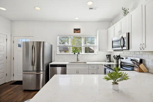 a kitchen with stainless steel appliances a sink a refrigerator a counter space and a window