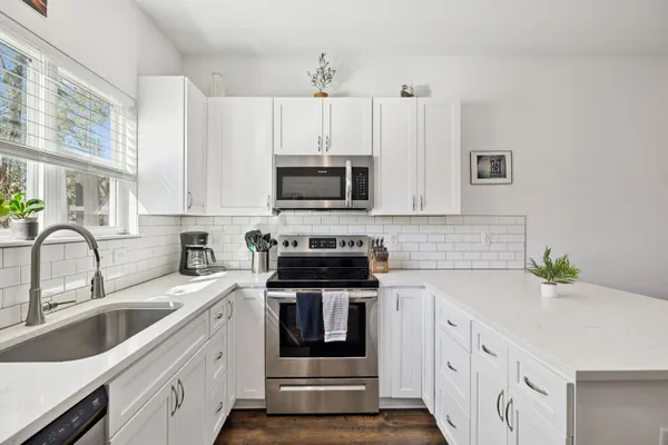 a kitchen with granite countertop a sink dishwasher a stove and a refrigerator with wooden cabinets