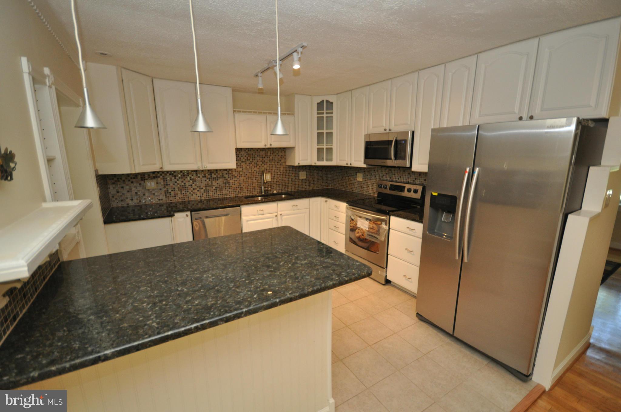18314 Sharon Road Triangle, VA 22172 - Photo 3 of 30 a kitchen with stainless steel appliances granite countertop a refrigerator a stove and a sink with wooden floor