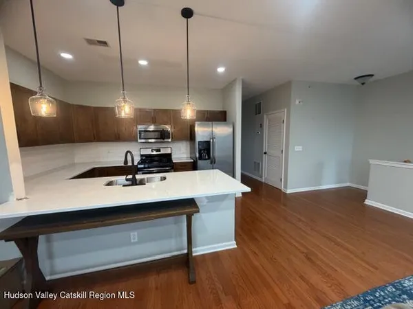 a view of a kitchen with kitchen island a sink stainless steel appliances and a fireplace