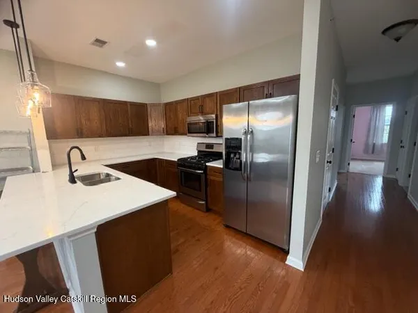 a kitchen with stainless steel appliances kitchen island granite countertop a refrigerator a sink a stove and island with wooden floor