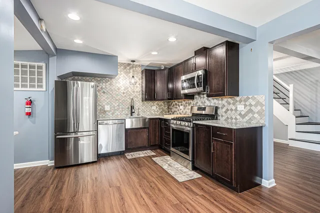 a kitchen with stainless steel appliances kitchen island granite countertop a refrigerator and a stove top oven