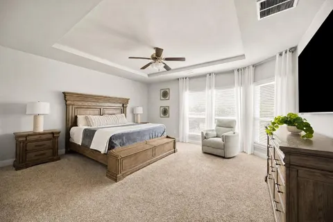 a bedroom with a bed couches and a flat tv screen