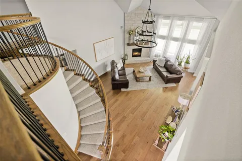 a view of a livingroom with furniture staircase wooden floor and windows