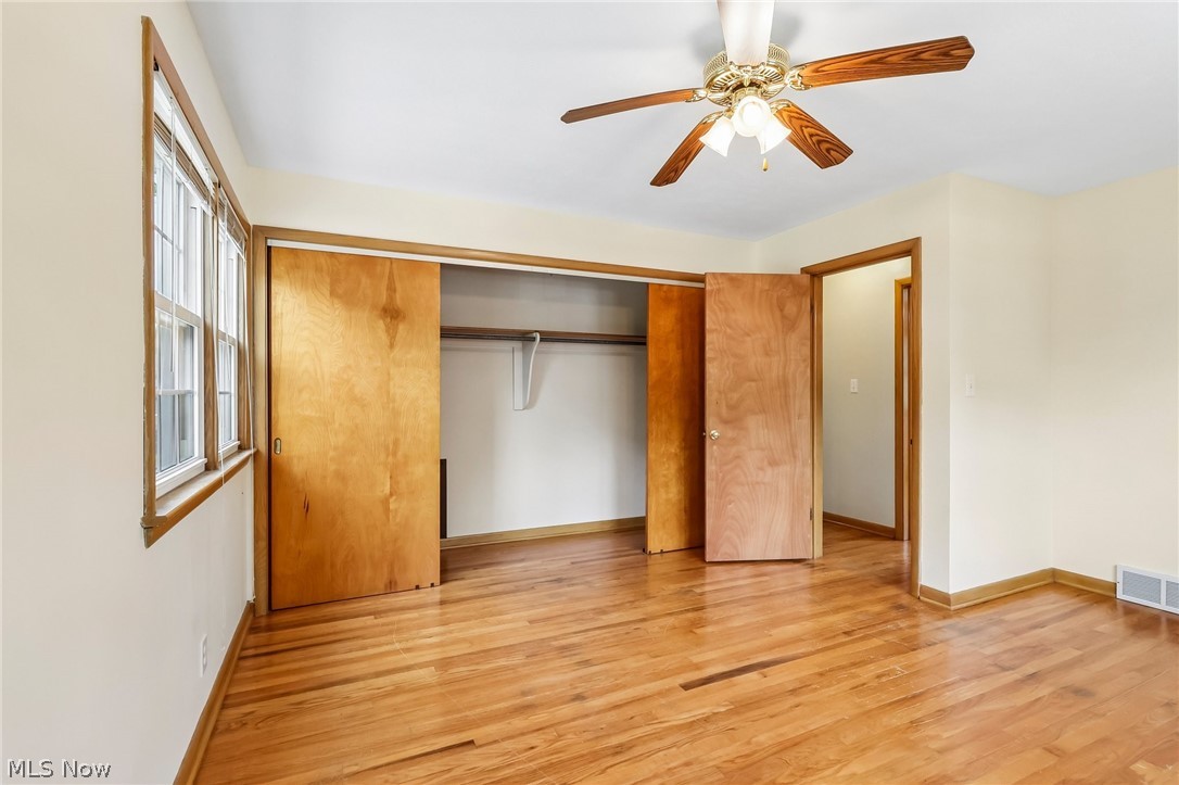1638 South Cleveland Massillon Road Akron, OH 44321 - Photo 14 of 37 Spacious room featuring hardwood flooring, a ceiling fan with light fixture, a window with natural wood trim, and a built-in closet with sliding wood doors