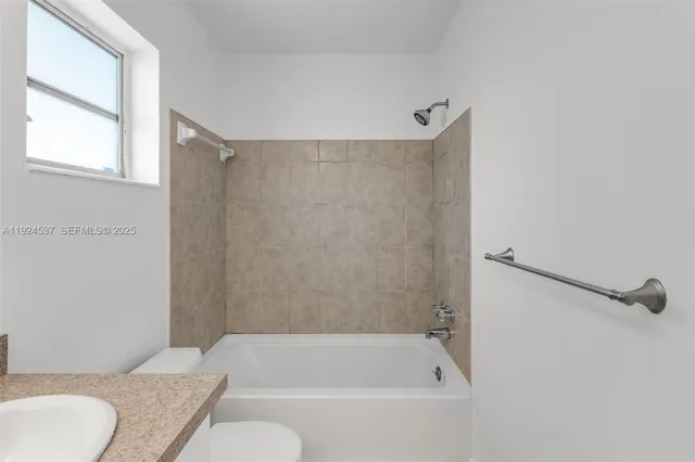 a bathroom with a granite countertop bathtub shower sink and toilet