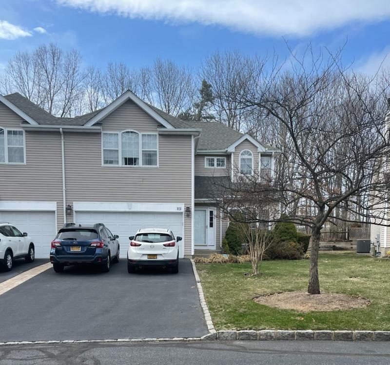 View of front of home featuring an attached garage, aphalt driveway, a front yard, and central AC unit