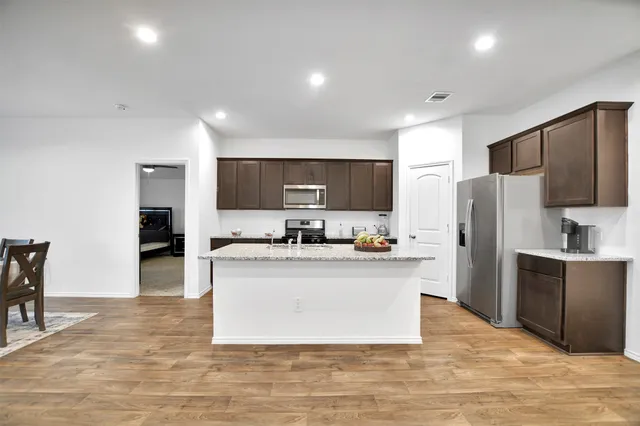 a kitchen with a stove a refrigerator and a dining table with wooden floor