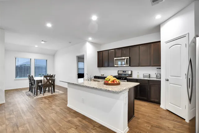 a kitchen with stainless steel appliances granite countertop a sink stove microwave and refrigerator