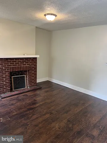 an empty room with wooden floor and fireplace