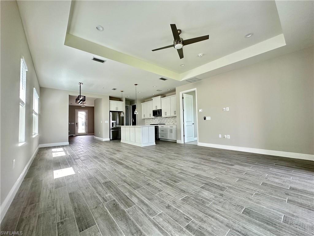 4580 Centaurus Circle Naples, FL 34120 - Photo 3 of 25 Unfurnished living room featuring a ceiling fan, wood tiled floors, a tray ceiling, and recessed lighting