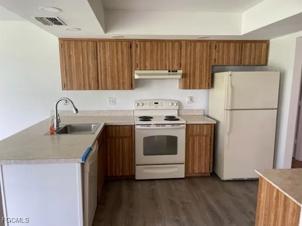 a kitchen with a sink a refrigerator and wooden cabinets