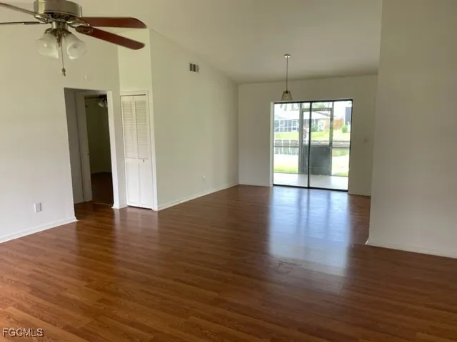 a view of an empty room with wooden floor and a window