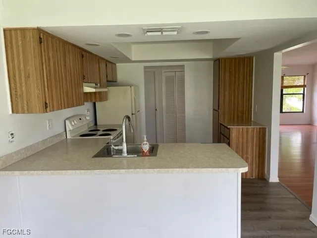 a kitchen with a sink a refrigerator and wooden cabinets