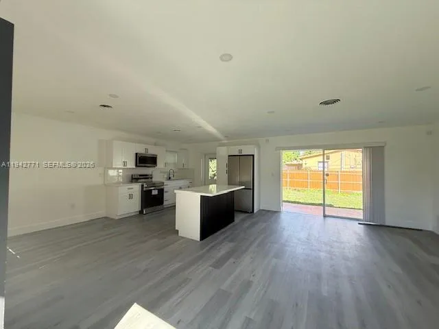 a view of a kitchen with wooden floor and stainless steel appliances