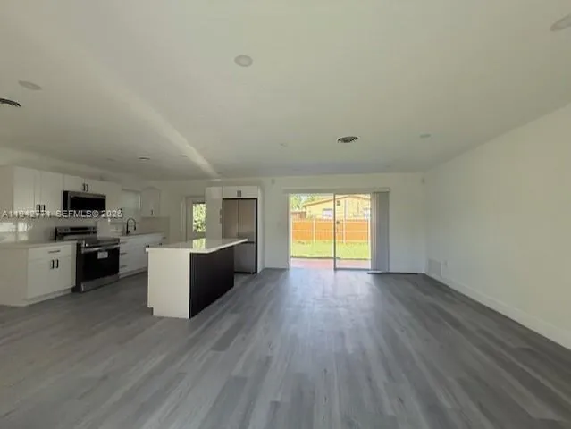 a view of a kitchen with wooden floor and a window