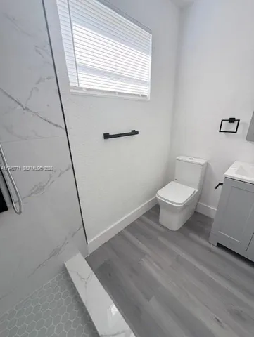 a bathroom with a sink a toilet a window and vanity