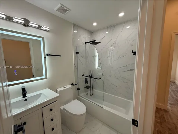 a bathroom with a granite countertop sink toilet and shower