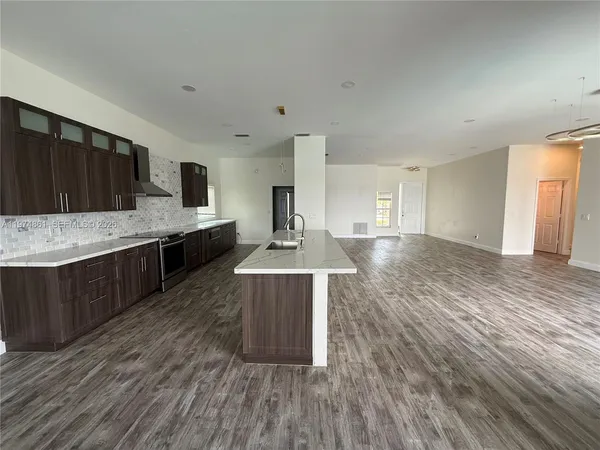a large kitchen with kitchen island a sink dishwasher a stove and a wooden floors