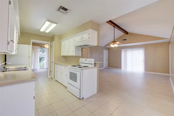 an empty room with wooden floor and a kitchen