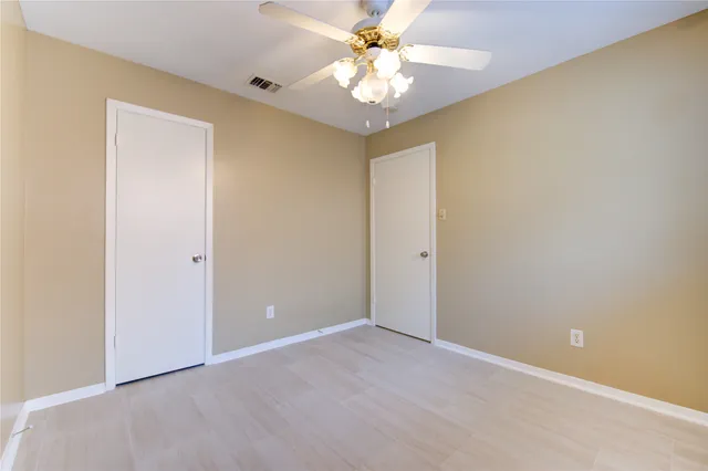 an empty room with windows and fan