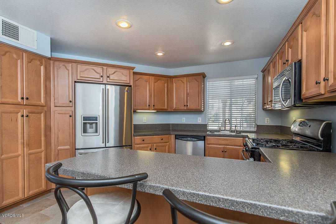 1745 Empty Saddle Road Simi Valley, CA 93063 - Photo 11 of 29 a kitchen with stainless steel appliances granite countertop a refrigerator a stove a sink a dining table and chairs with wooden floor