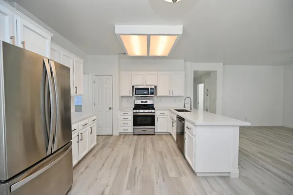 a kitchen with a refrigerator a stove top oven a sink and dishwasher with wooden floor