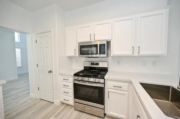 a view of a kitchen with wooden floor and electronic appliances