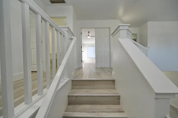 an empty room with wooden floor and ceiling fan