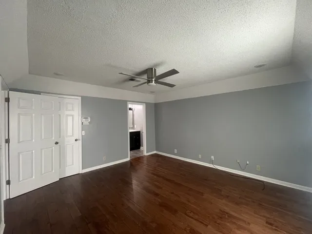 an empty room with wooden floor fan and windows