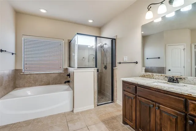 a bathroom with a granite countertop sink mirror bathtub and next to a window