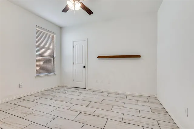 a view of an empty room with window and chandelier fan