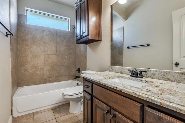 a bathroom with a granite countertop sink a toilet and bathtub
