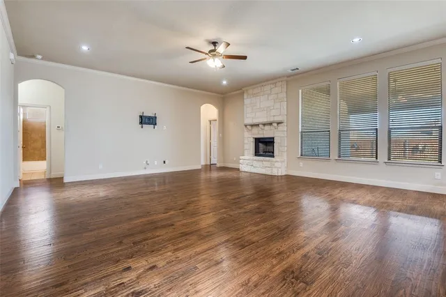 an empty room with wooden floor chandelier and windows