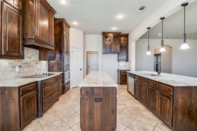 a large kitchen with stainless steel appliances granite countertop a stove a sink dishwasher and a refrigerator