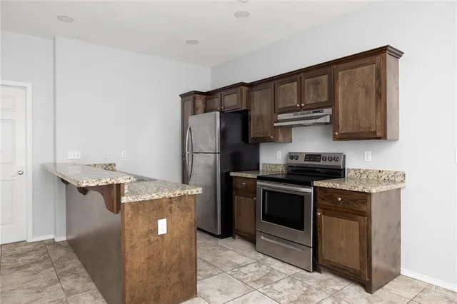 a kitchen with stainless steel appliances granite countertop a stove a refrigerator and a sink