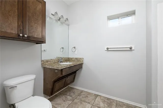 a bathroom with a granite countertop toilet and a sink