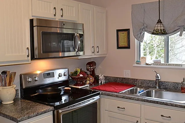 a kitchen with granite countertop a sink a counter space cabinets and stainless steel appliances
