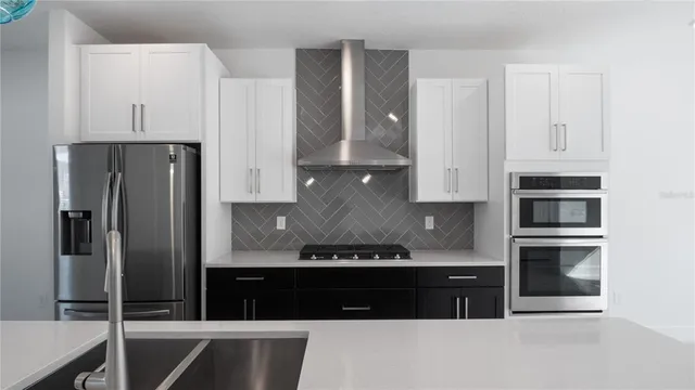 a kitchen with stainless steel appliances granite countertop a refrigerator a stove and a sink