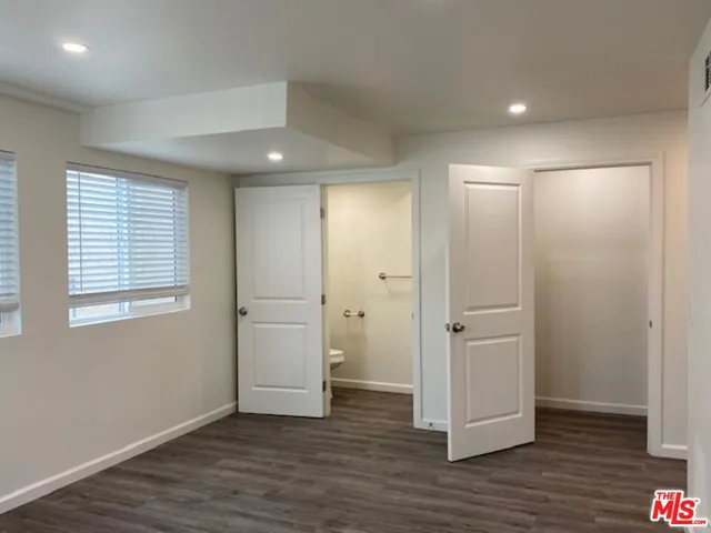 an empty room with wooden floor & windows