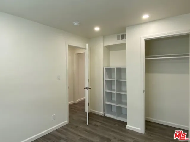 a view of empty room with wooden floor and closet