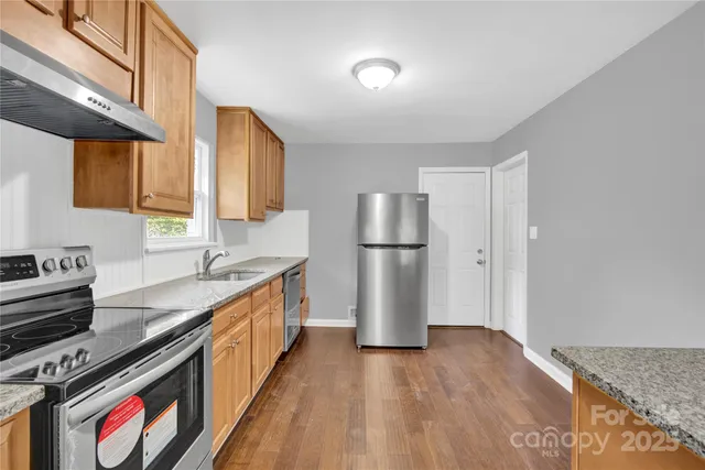 a kitchen with stainless steel appliances granite countertop a refrigerator a stove and a sink