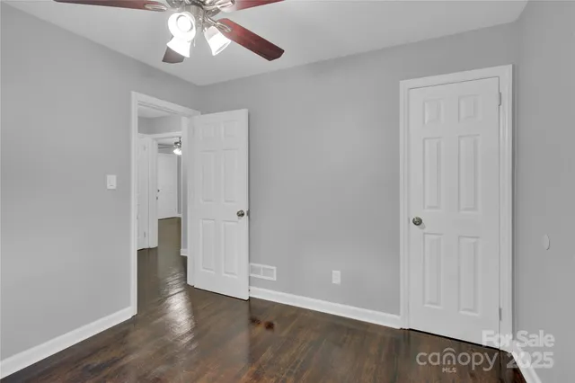 an empty room with wooden floor and ceiling fan