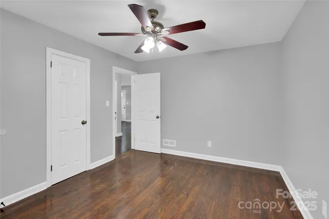an empty room with wooden floor and ceiling fan